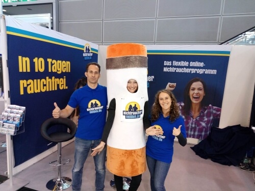 Die NichtraucherHelden mit Zigaretten-Maskottchen am Messestand